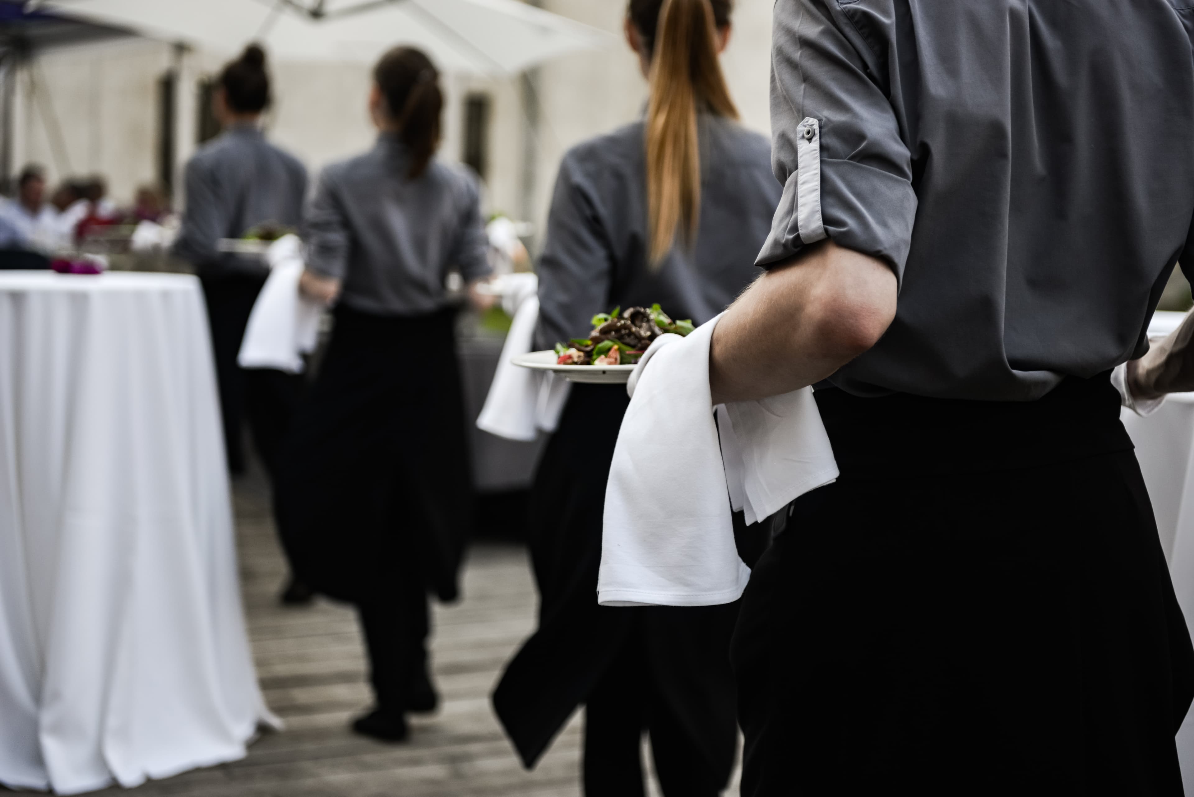 Event servers carrying plates in a well-lit venue